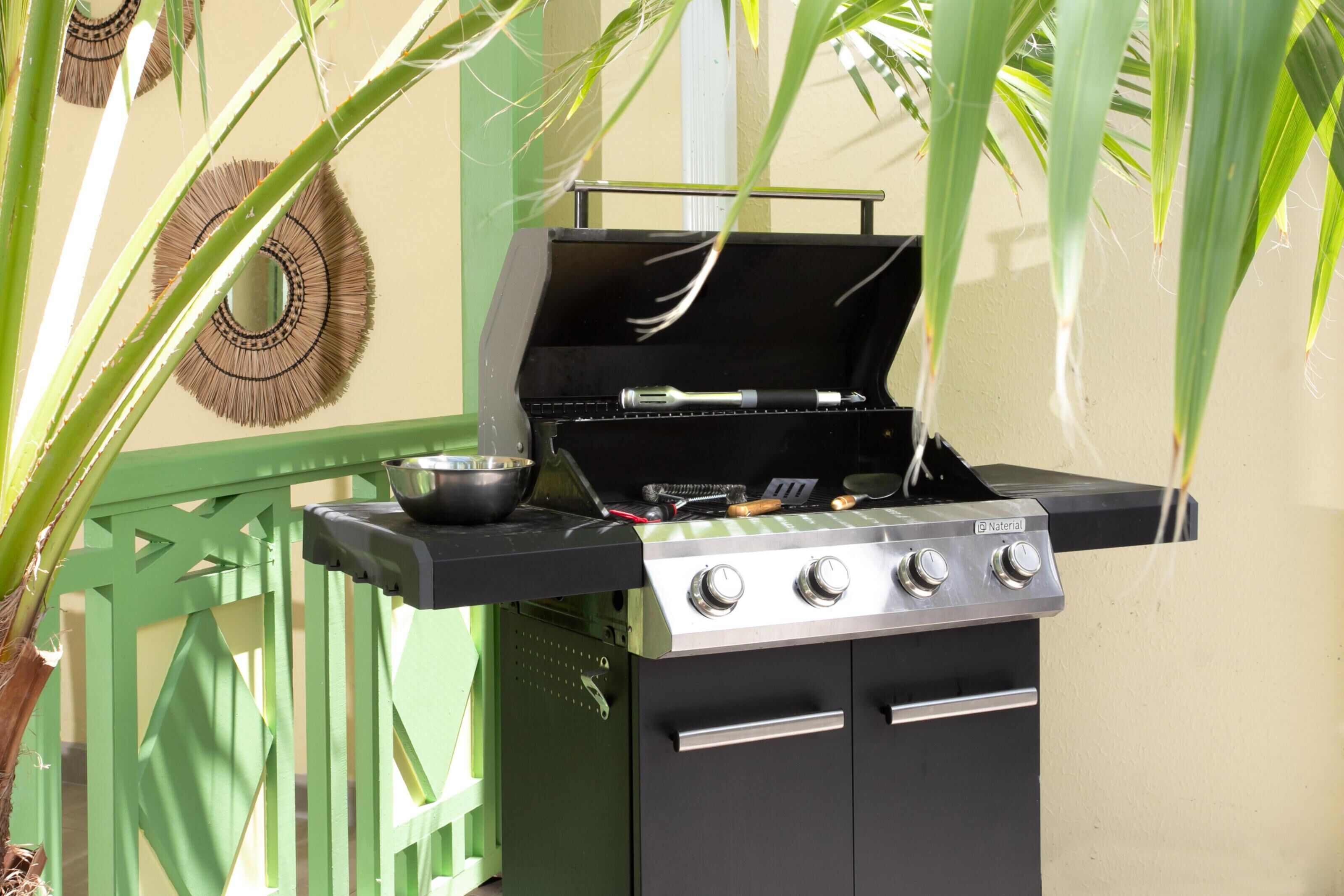 Una parrilla con diseño negro y plateado, una olla y un cepillo sobre la parrilla.