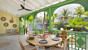 Un espace extérieur abrité, aménagé pour les repas, avec une table ronde pour quatre personnes, entourée de chaises en bois.