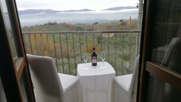 A balcony with a table set for two, overlooking a scenic landscape. - The Sleeping Lions House (Pietrapiana)