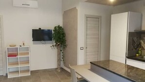 A modern kitchen with a flat-screen TV mounted on the wall, a built-in oven, and a countertop with a sink. - The Sleeping Lions House (Pietrapiana)