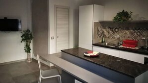 A modern kitchen with a marble countertop, white cabinets, and a tiled backsplash. - The Sleeping Lions House (Pietrapiana)