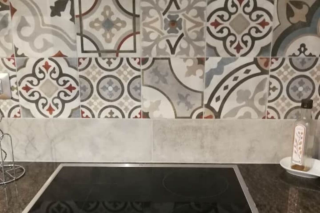 Una cucina con piastrelle decorate e un piano di lavoro nero.