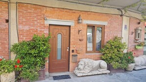 A brick building with a wooden door, a window, and a stone lion statue in front. - The Sleeping Lions House (Pietrapiana)
