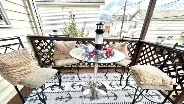 A patio with two cushioned chairs, a glass table, and a decorative lantern.