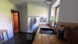 A modern kitchen with a wooden countertop, a sink, and a window. There is a small trash bin and a stool. - Private suite with sauna and garden (Etzling)