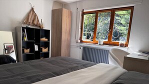 A bedroom with a bed, a wardrobe, a radiator, and a window with a view of greenery. - Private suite with sauna and garden (Etzling)