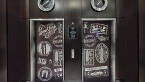 Ascensore decorato a tema New York, con immagini dell'Empire State Building e una mappa della metropolitana.