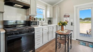 Una cocina moderna con armarios blancos, una estufa negra y ventana con vistas a la playa.