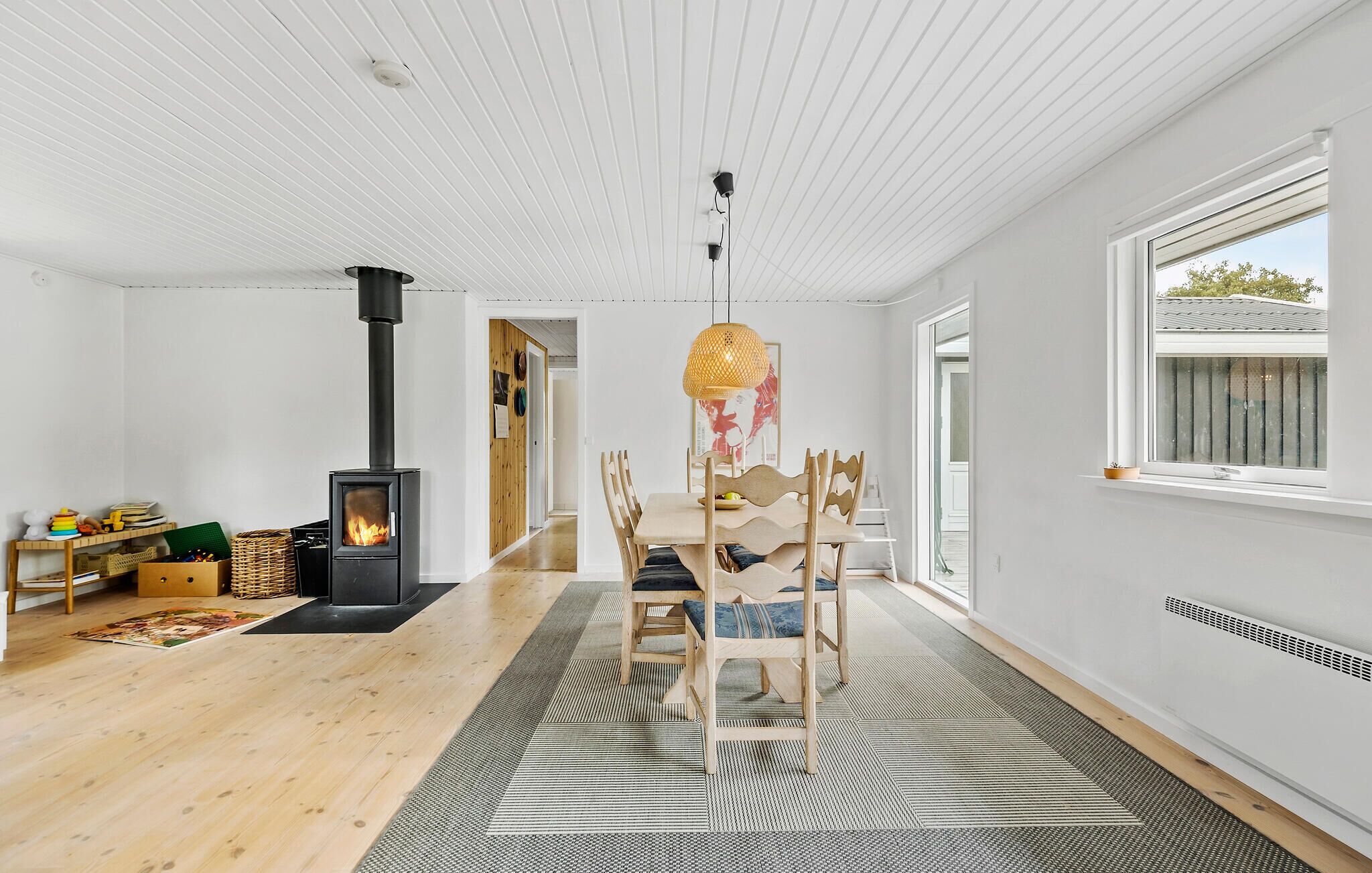 A spacious room with a modern fireplace, wooden furniture, and a large window.