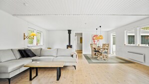 A modern living room with a sofa, a wooden coffee table, a dining area with a table and chairs, and a fireplace. - Gorgeous home in Sjællands Odde with WiFi (Sjællands Odde)