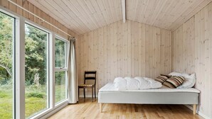 A bedroom with a bed, a chair, and large windows. - Gorgeous home in Sjællands Odde with WiFi (Sjællands Odde)