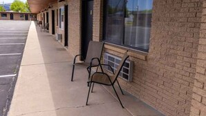 Un motel con estacionamiento techado, asientos al aire libre y fachada de ladrillo.
