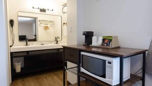 Cocina compacta equipada con microondas, cafetera y un lavamanos pequeño.