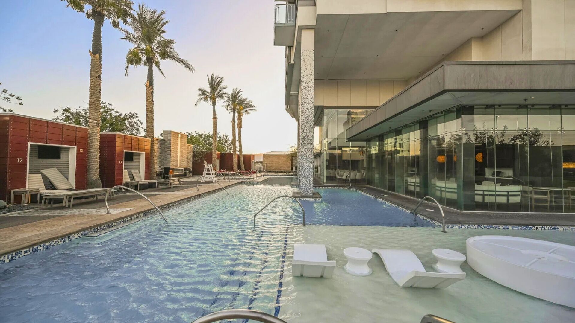 A swimming pool with lounge chairs and a glass-enclosed area.