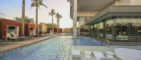 A swimming pool with lounge chairs and a glass-enclosed area.