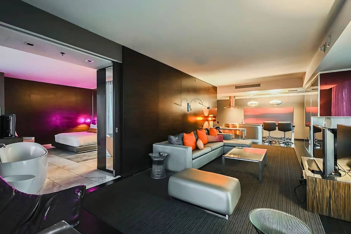 Een moderne hotelkamer met een zithoek, een afzonderlijke slaapkamer en een eethoek.