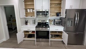 A modern kitchen with white cabinets, a built-in oven, a microwave, a toaster, and a stainless steel refrigerator. - River Trail Stays - Rivers Edge (Tucson)