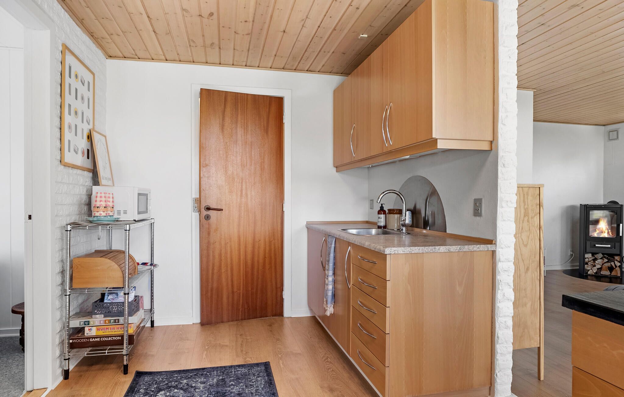 Cuina compacta amb armaris de fusta, un solllador integrat i una cuina.