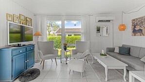 A modern living room with a TV, sofa, chairs, and a dining table.