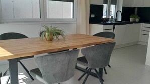 Cuina moderna amb taula de fusta i dues cadires grises, finestra amb cortines i vista al carrer.