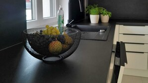 Cuina moderna amb taulell negre, un rentaplat i plantes en testos.