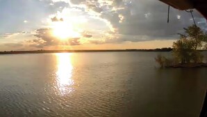 Un lago tranquilo con un atardecer al fondo.