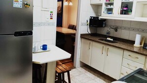 Una cocina compacta con refrigerador, mesa de comedor y microondas.