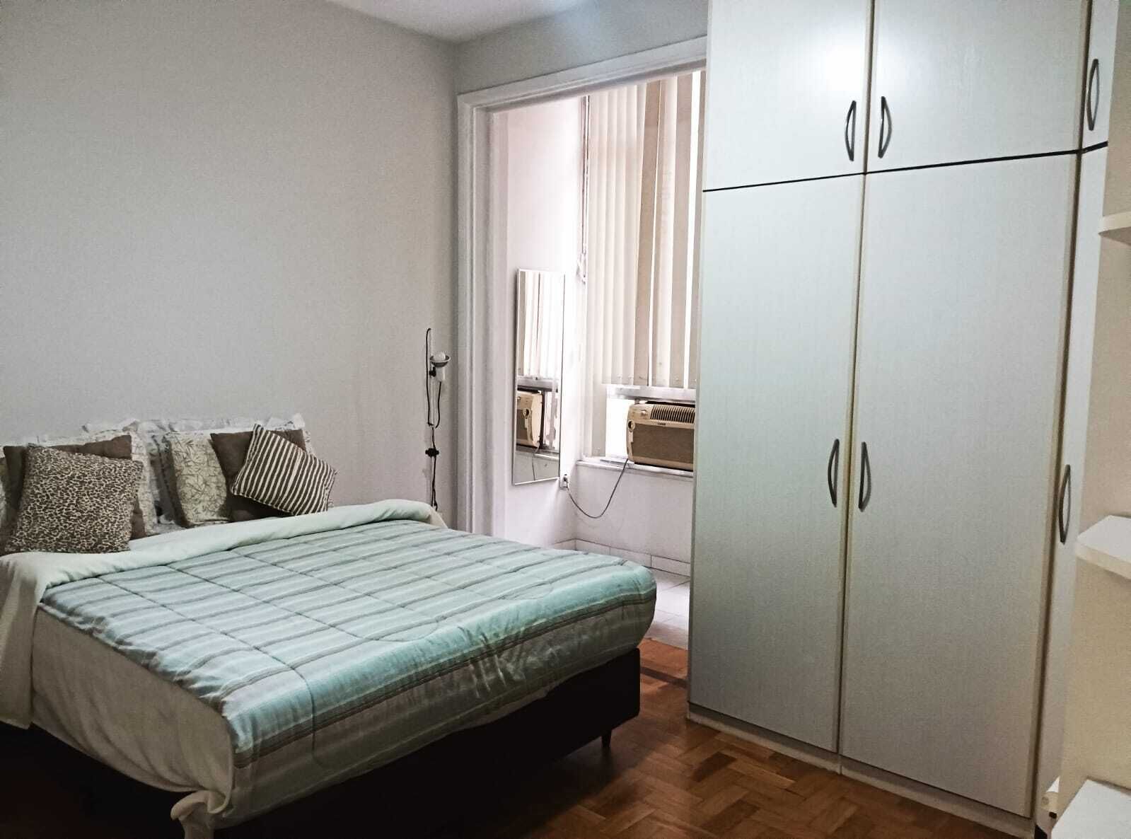 A bedroom with a bed, a wardrobe, and a window with blinds.