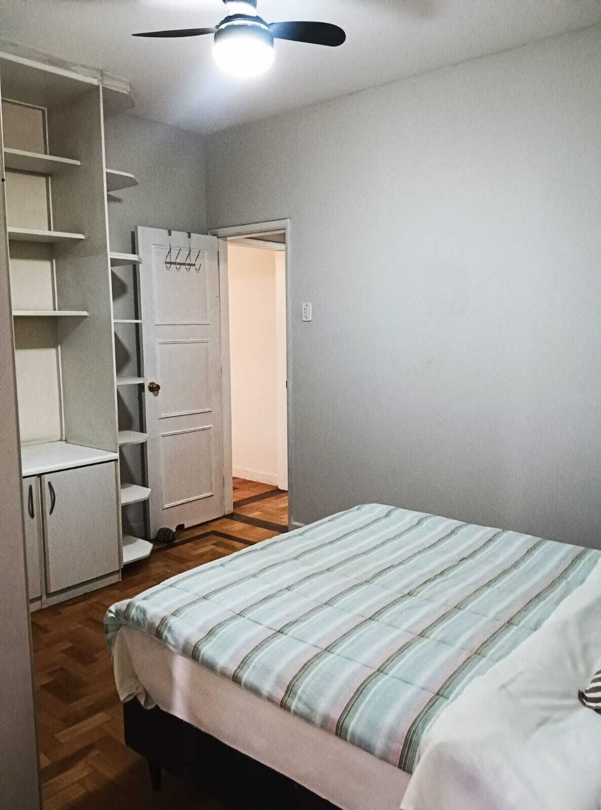 Een slaapkamer met een bed, een kledingkast en een plafondventilator.
