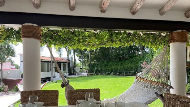 Une table dressée pour le dîner, avec vue sur un jardin et un hamac.