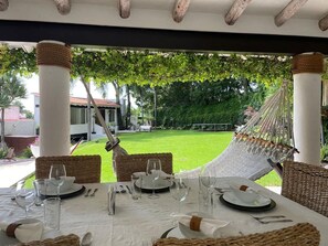 Een eettafel met uitzicht op een tuin en een hangmat.