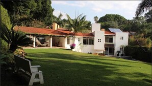 Une maison moderne avec un toit recouvert de tuiles rouges, un patio abrité et un panneau solaire.