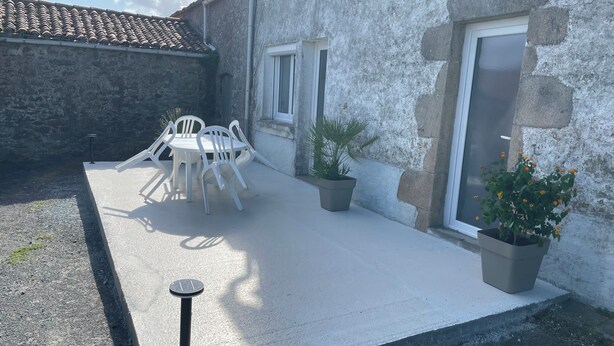 A patio area with a table and chairs, a potted plant, and a door. - Country house 20 minutes from Puy du Fou (Mortagne-sur-Sèvre)