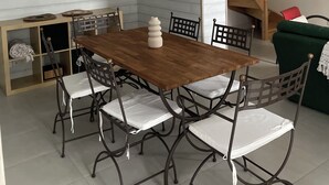 A dining area with a wooden table and metal chairs, a hanging light fixture, and a staircase in the background. - Country house 20 minutes from Puy du Fou (Mortagne-sur-Sèvre)