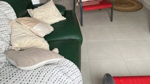 A living room with a green sofa, a red chair, and a staircase. - Country house 20 minutes from Puy du Fou (Mortagne-sur-Sèvre)