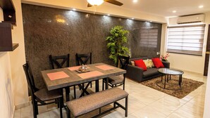 A modern living room with a dining area, featuring a ceiling fan, a sofa with red cushions, a coffee table, and a large plant. - Flamingos 45 - Vacation Home for rent 5 min from Ixtapa's hotel zone! (Ixtapa-Zihuatanejo)