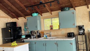 A kitchen with wooden beams, a black refrigerator, a stove, and light blue cabinets.
