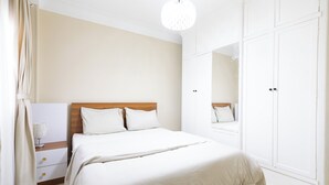 A bedroom with a bed, a nightstand, a wardrobe, and a mirror. - 2BRs CityStar Mall Apartment (Al Golf, Nasr City)