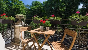 A wooden table with two chairs on a balcony with wrought iron railings, potted plants, and a stone pillar. - Vanilla 6, 2bdr 2 bth apartment 5min from Krakow's Main Square (Kraków)