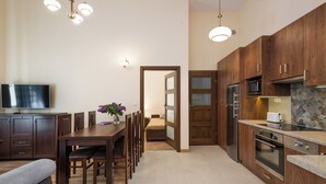 A modern kitchen with wooden cabinets, a dining area with a table and chairs, and a TV on the left. - Vanilla 6, 2bdr 2 bth apartment 5min from Krakow's Main Square (Kraków)