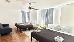 A modern hotel room with a large bed, a sofa, a chair, and a small table. - Spacious delray suite (Delray Beach)