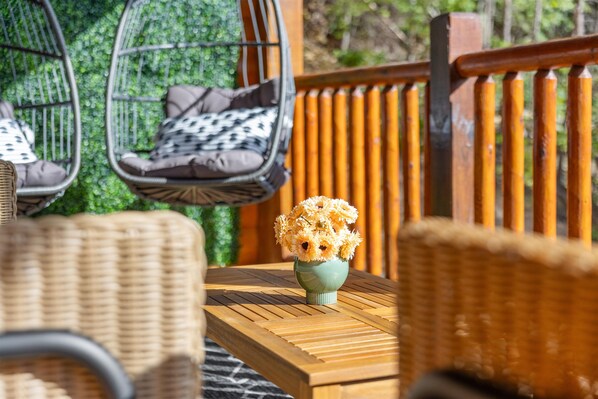 Wicker furniture with cushions, a wooden table, and a vase of flowers. - ๐ฎ Arcade & Theater + ๐โโ๏ธ Pool & Hot Tub, ๐ Sleeps 14, ๐ข Near Dollywood (Pigeon Forge)