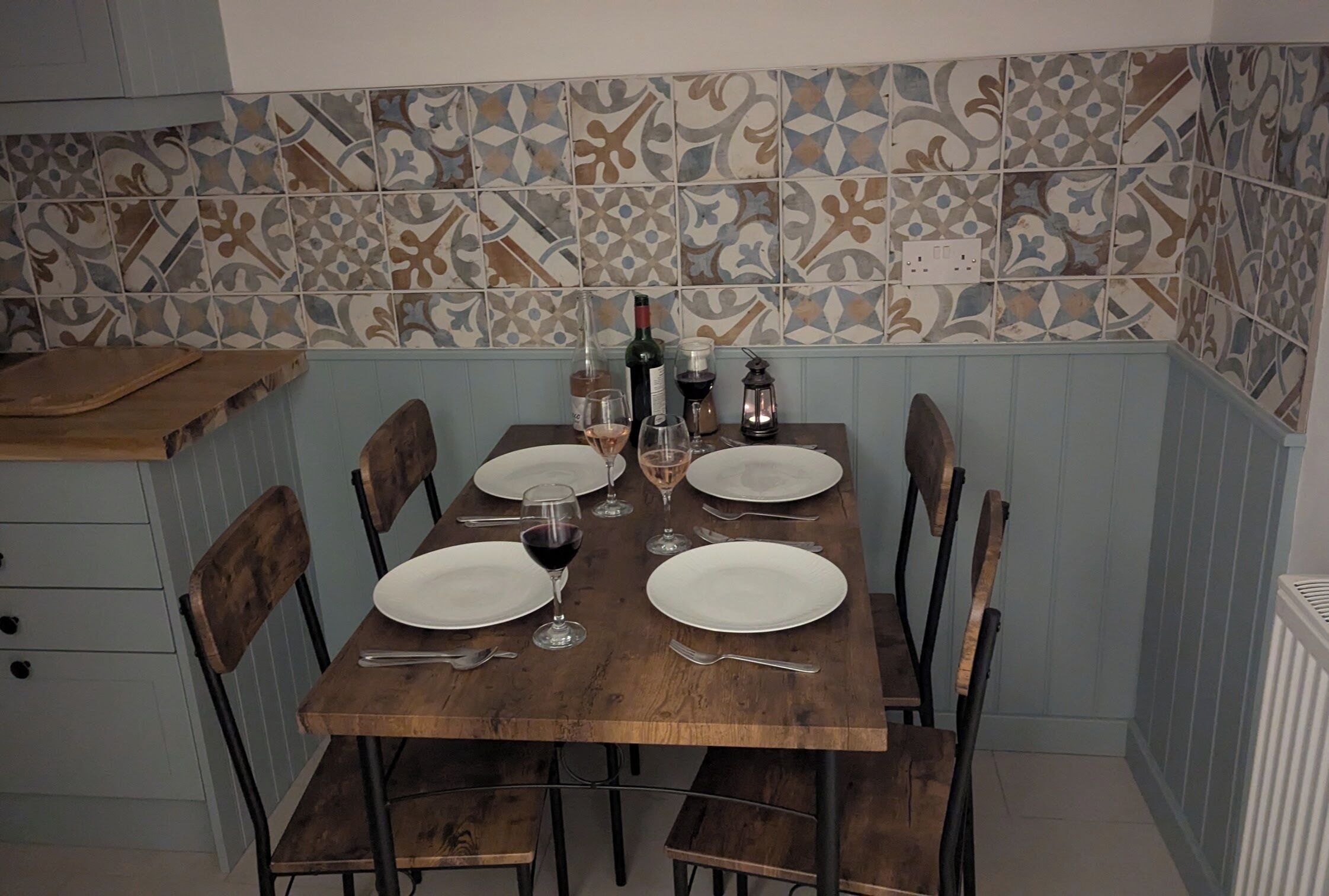 Une table à manger dressée pour quatre personnes, avec des verres à vin, des assiettes et des couverts.