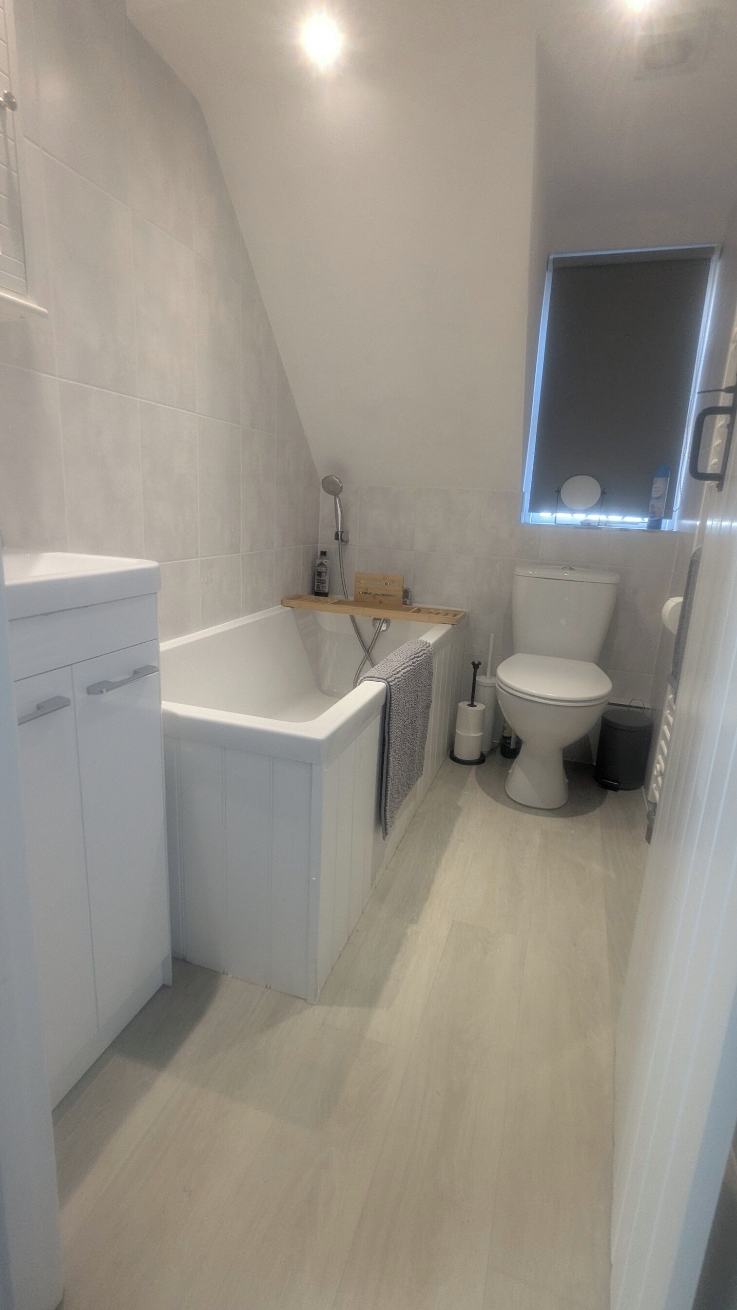 A modern bathroom with a freestanding bathtub, a toilet, and a window.