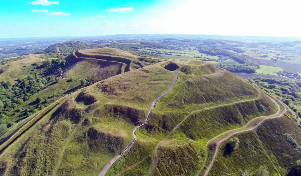 Vue aérienne d’un paysage vallonné, avec une route sinueuse.
