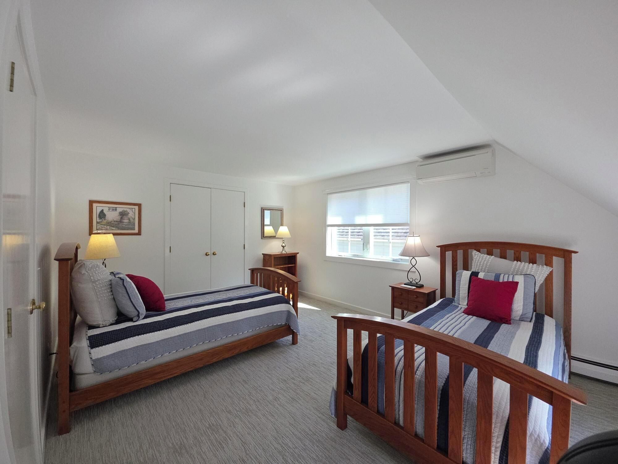 A bedroom with two beds, a window, and a door.