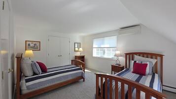 A bedroom with two beds, a window, and a door.