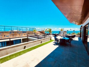 A rooftop terrace with a view of the ocean, outdoor seating, and a modern architectural design. - Oásis Porto de Galinhas - Flat na Praia (Ipojuca)