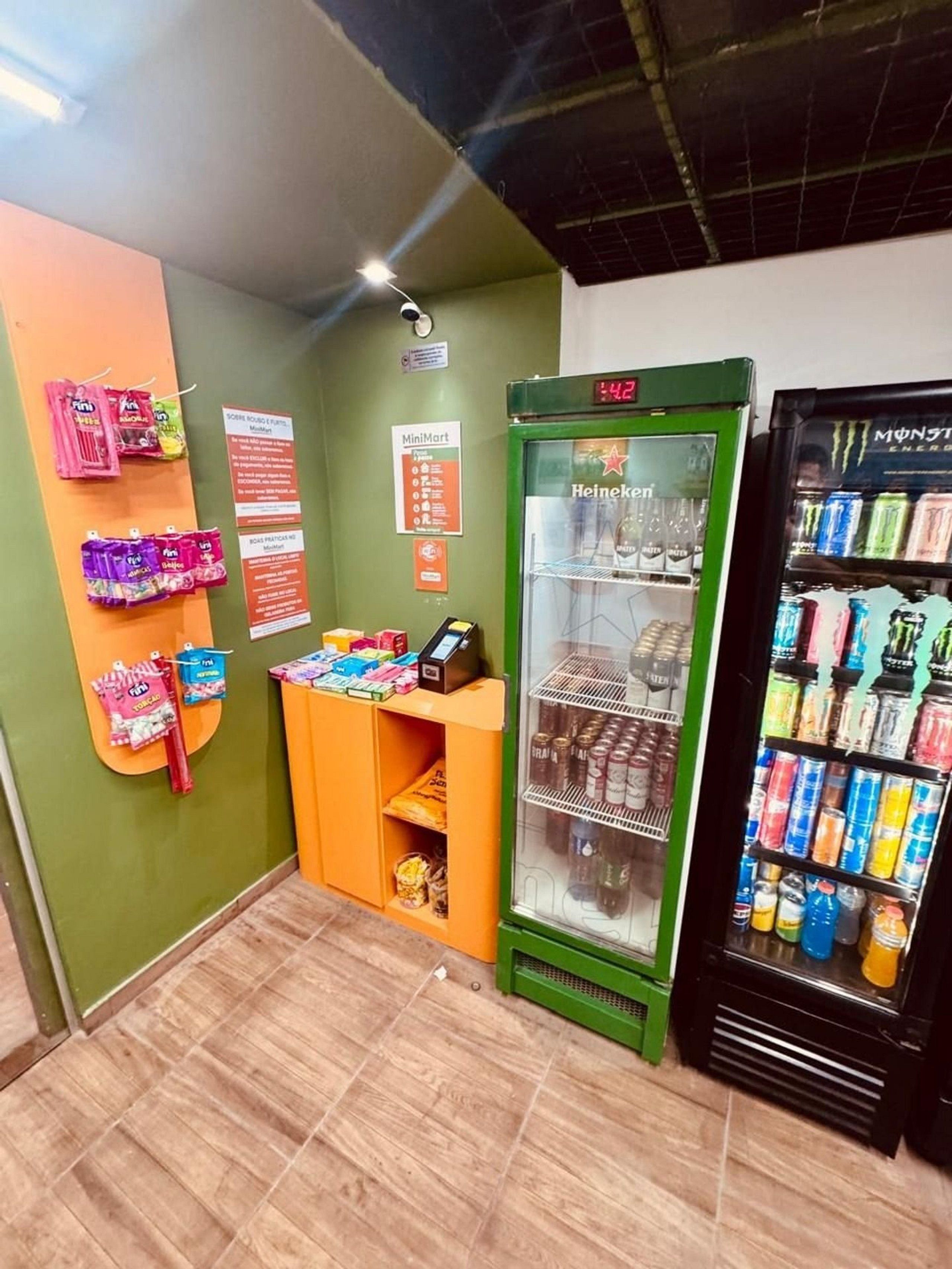 Un quiosco MiniMart con una variedad de aperitivos y bebidas, un refrigerador de Heineken y un enfriador de Monster Energy.