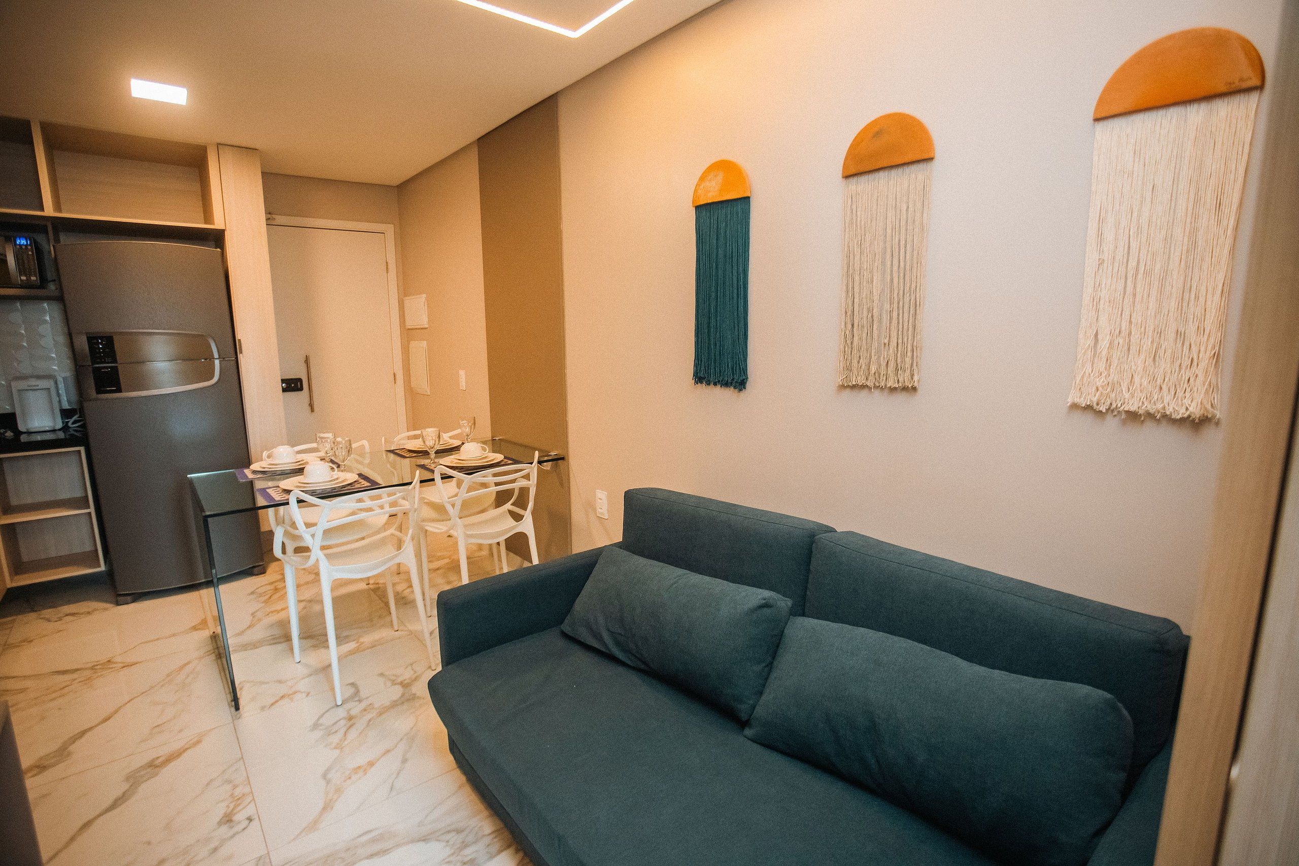 A compact living space with a sofa, dining table, chairs, a refrigerator, and a kitchen area.